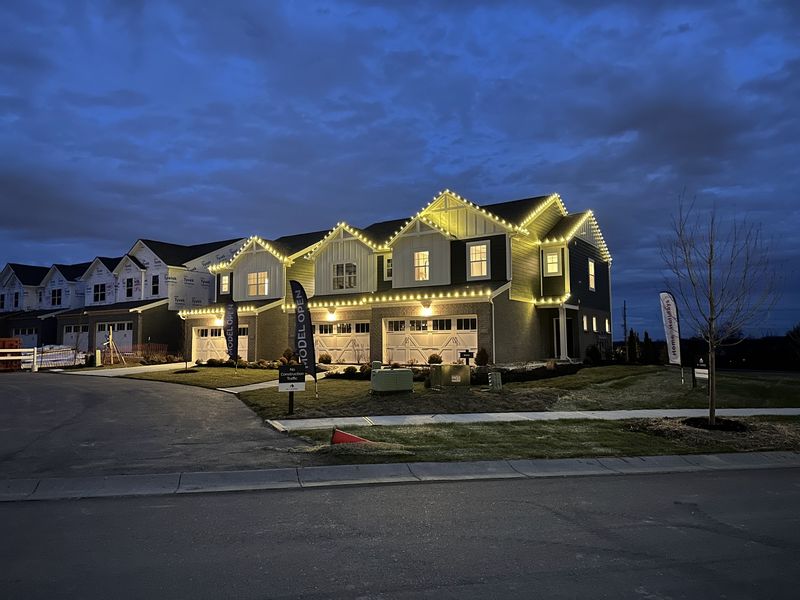 Row of townhomes with warm white lights on each roof peak